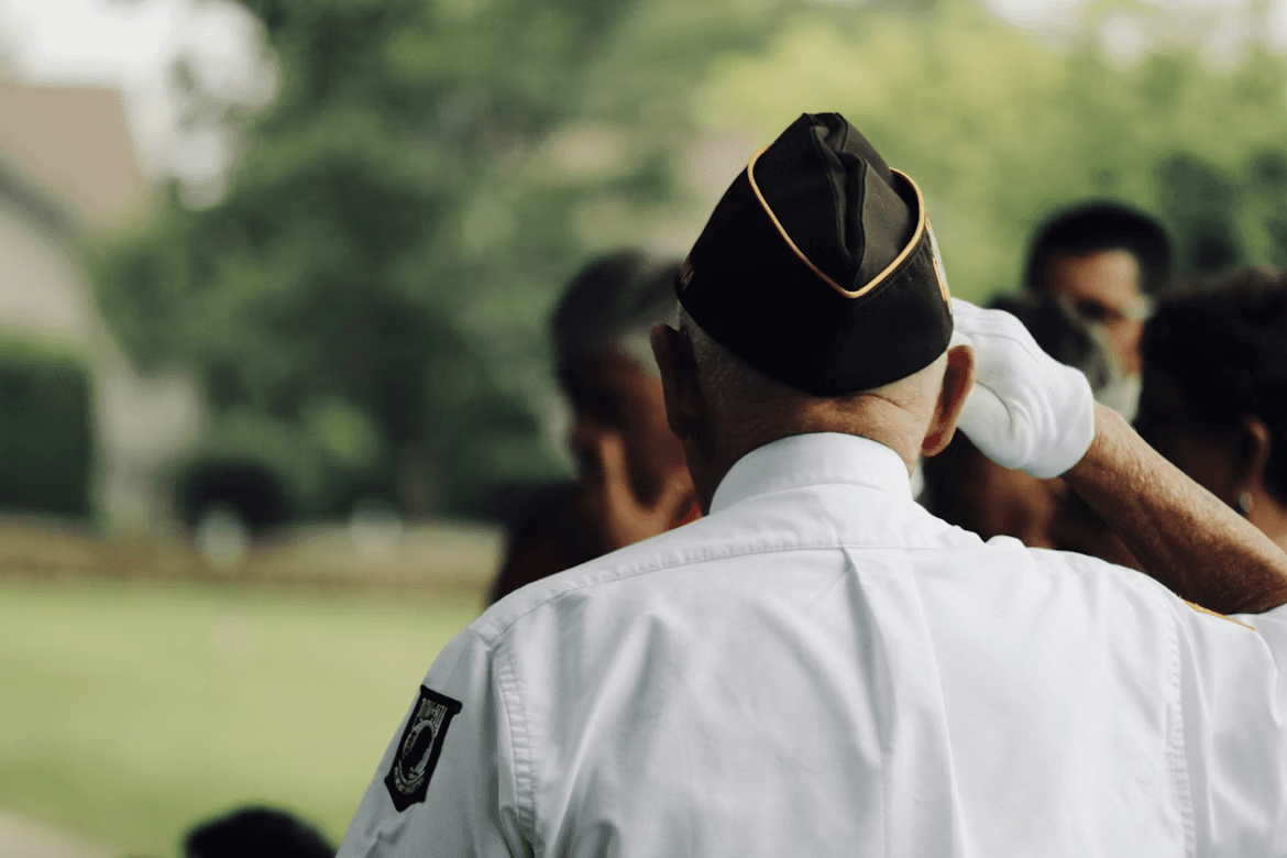 A veteran in uniform saluting at an outdoor ceremony