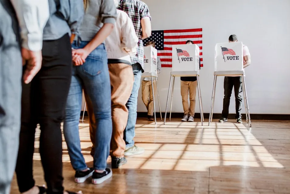 Voters at polling booths beneath an American flag